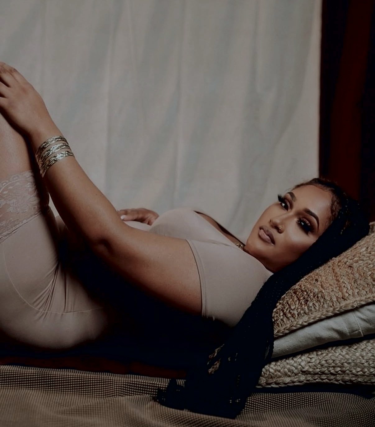 A woman lounging on soft linen, skin glowing